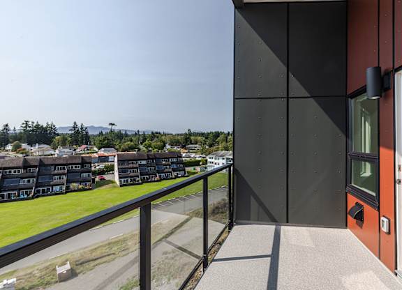 A modern building with a balcony overlooking a residential area.