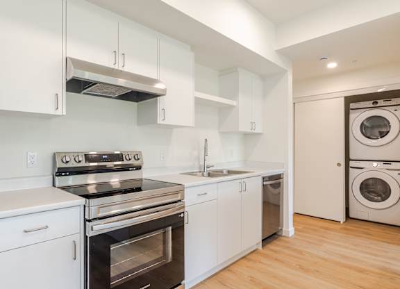 A modern kitchen with white cabinets and stainless steel appliances.