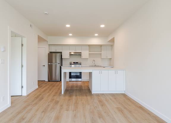 A kitchen with white cabinets and a wooden floor.