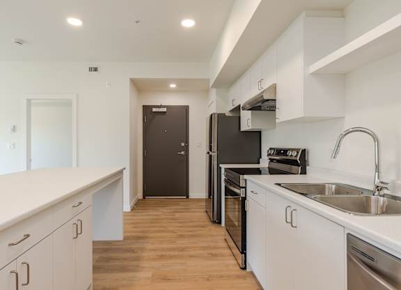 A kitchen with white cabinets and a black refrigerator.