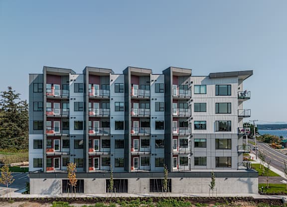 A modern apartment building with balconies overlooking the ocean.