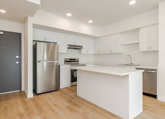 A modern kitchen with a white island and stainless steel appliances.