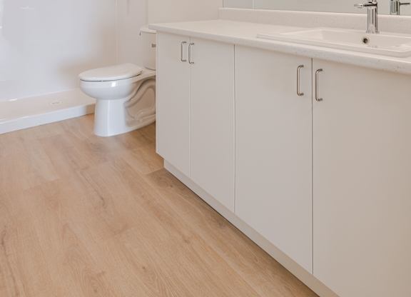 A white bathroom with a toilet, sink, and mirror.