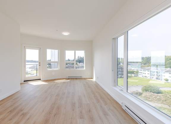 A large empty room with wooden floors and large windows.