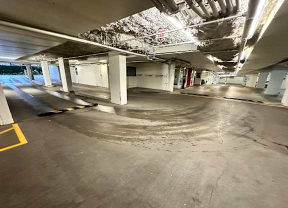 A parking garage with a concrete floor and white pillars.