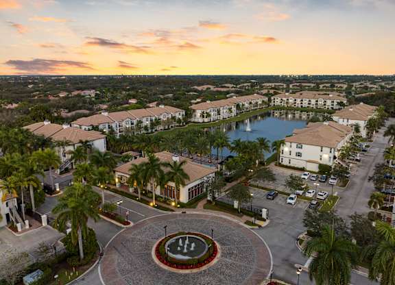 A sunset view of a resort with a fountain in the middle of a courtyard.