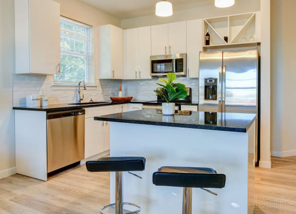 a kitchen with white cabinets and a counter with stools at Solo at North Bergen, North Bergen, NJ