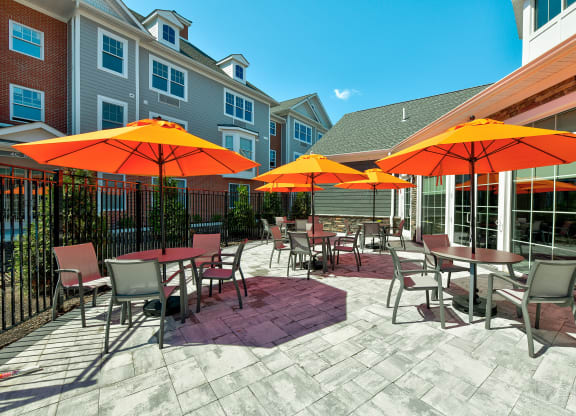a patio with tables and chairs and umbrellas  at Solo at North Bergen, North Bergen, New Jersey