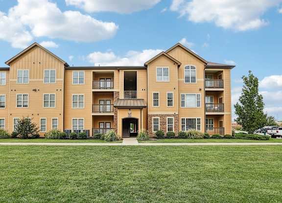 a large apartment building with a green lawn
