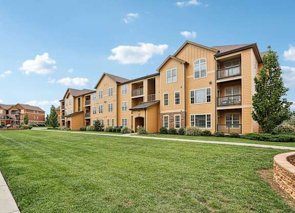the view of an apartment building with a green lawn