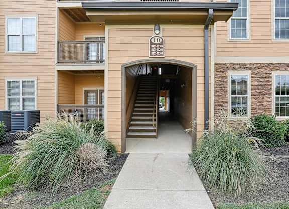 the entrance to an apartment building with stairs and a walkway