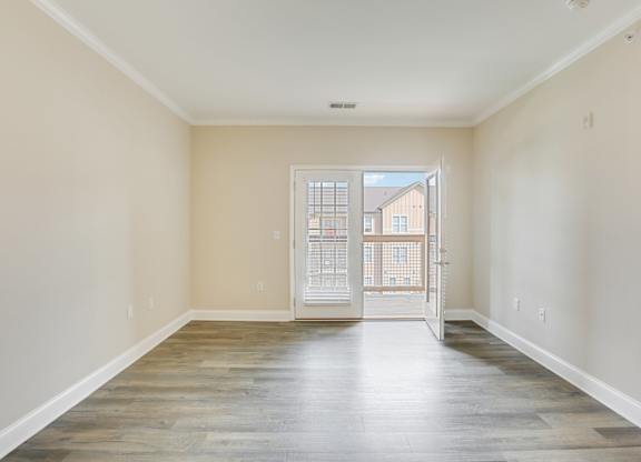 an empty living room with a door to a balcony