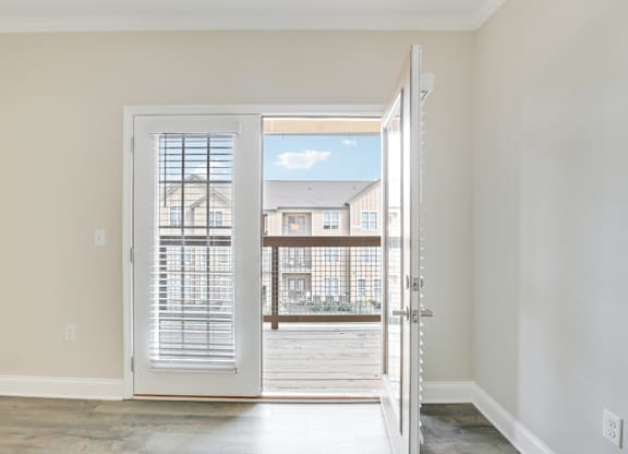 an empty living room with a door open to a balcony