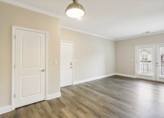 an empty living room with white doors and a window