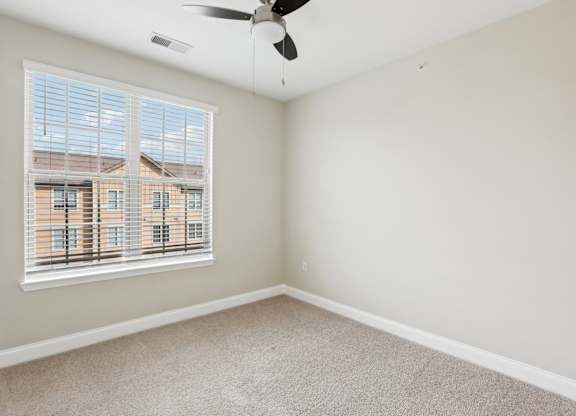 an empty room with a window and a ceiling fan