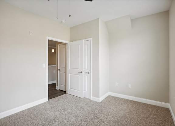 an empty bedroom with white doors and a door to a closet