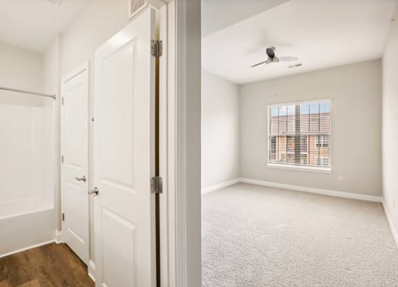an empty bedroom with white doors and a window