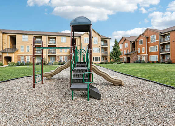 a playground with slides in front of an apartment complex