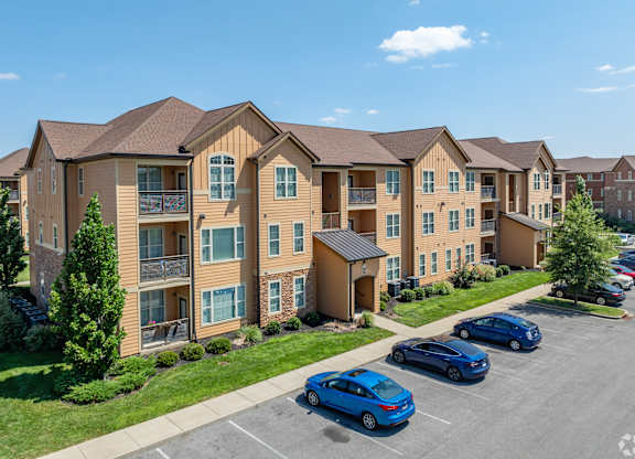 an apartment building with cars parked in a parking lot