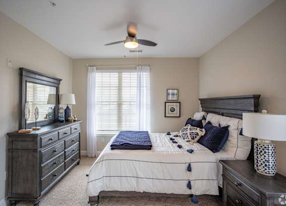 a bedroom with a bed and dresser and a ceiling fan