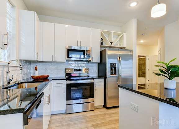 Modern apartment kitchen with white cabinetry and stainless steel appliances at The Rail North Bergen