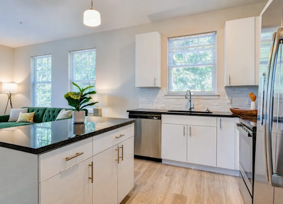A modern kitchen with white cabinets and a black countertop.