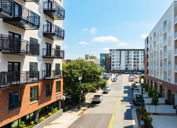 A street view of a residential area with cars parked on the side of the road.