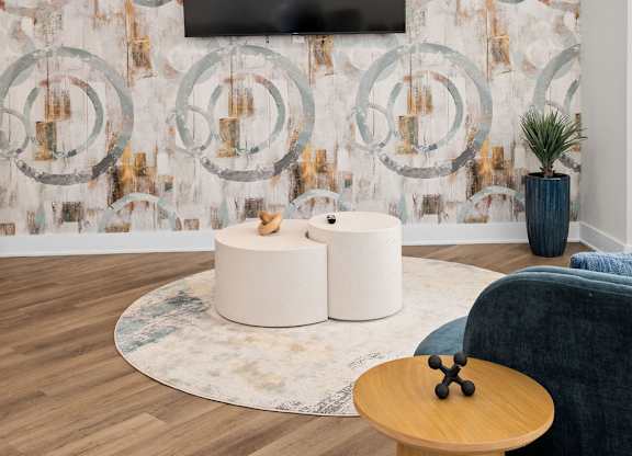 A living room with a television, two white ottomans, and a blue couch.