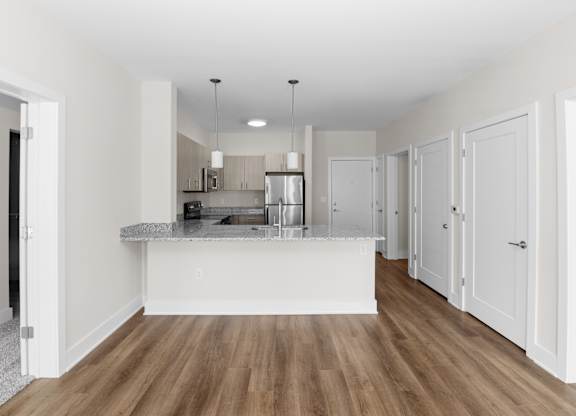 A kitchen with white cabinets and a wooden floor.