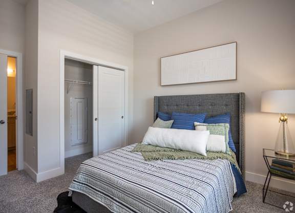 A bedroom with a bed, a nightstand, and a lamp.