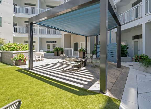A patio with a table and chairs is covered by a blue awning.
