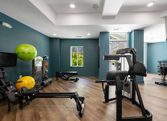 A gym with a variety of equipment including a treadmill, weights, and a bench.