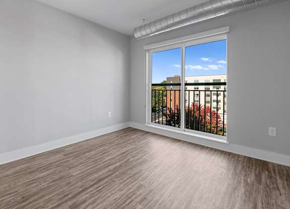 A room with a window overlooking a building with trees.