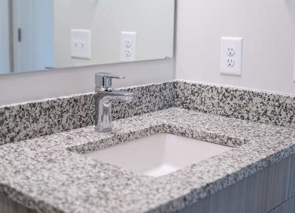 A bathroom sink with a granite countertop and a silver faucet at Novi Rise.