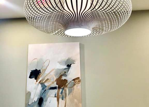 A modern art piece with a painting and a lamp hanging from the ceiling.