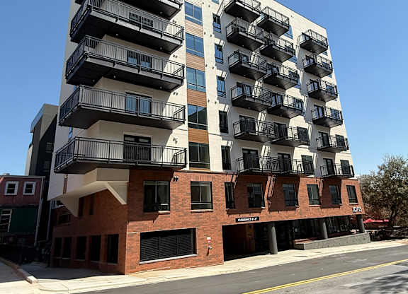 A modern multi-story building with balconies on the upper floors.