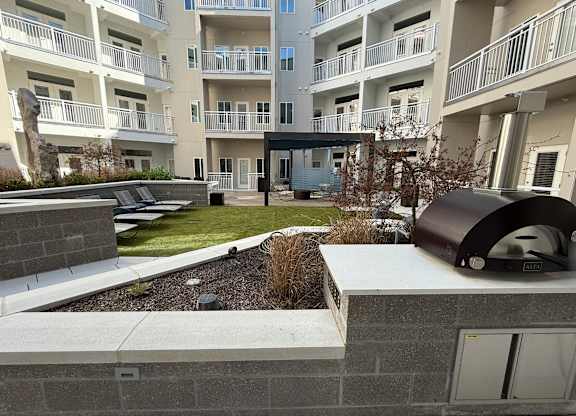 A modern apartment complex with a landscaped courtyard and a BBQ grill.