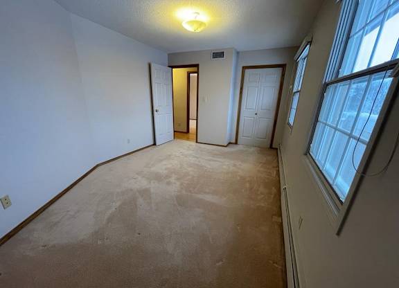 A room with a carpeted floor and a window on the right side.