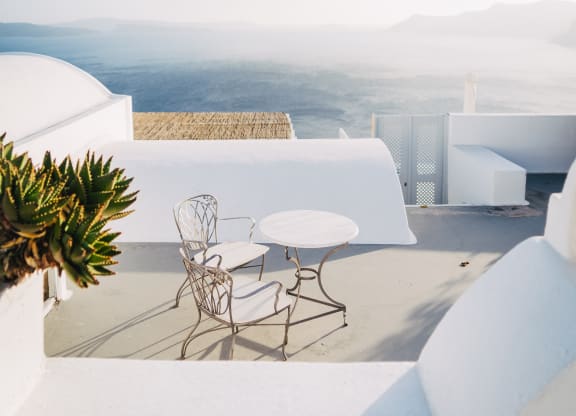 A table and chairs are on a patio overlooking a mountainous landscape.