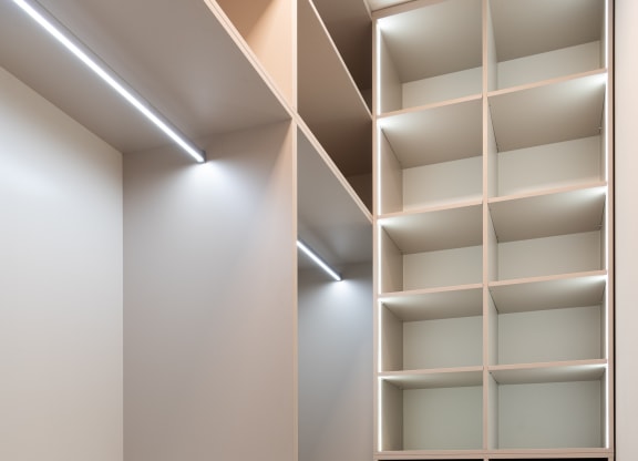 a walk in closet with white shelving and a wood floor