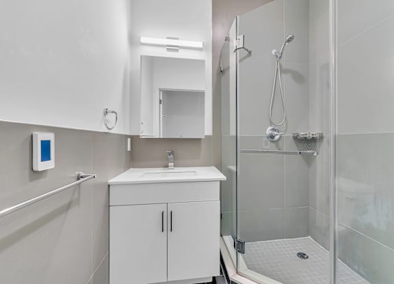 A white bathroom with a sink, mirror, and shower.