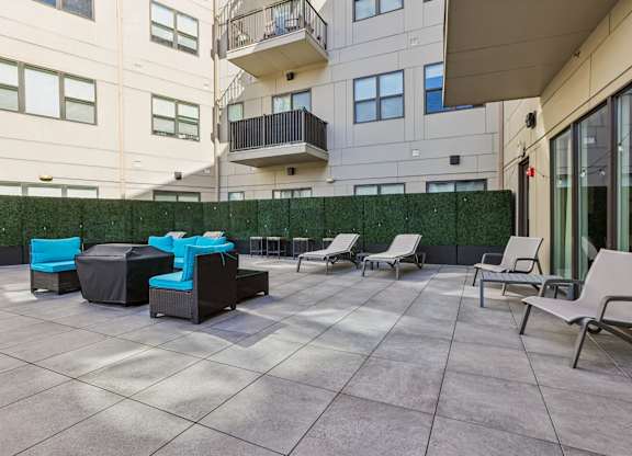 A patio with chairs and a table with a blue cushion.