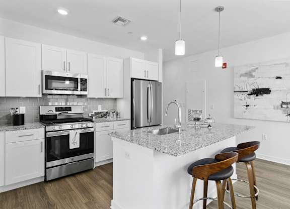 A modern kitchen with a white island and stools at 10 N. Main Apartments, New Jersey, 07885