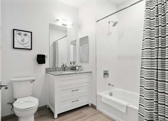 A white bathroom with a toilet, sink, and bathtub at 10 N. Main Apartments, Wharton 07885