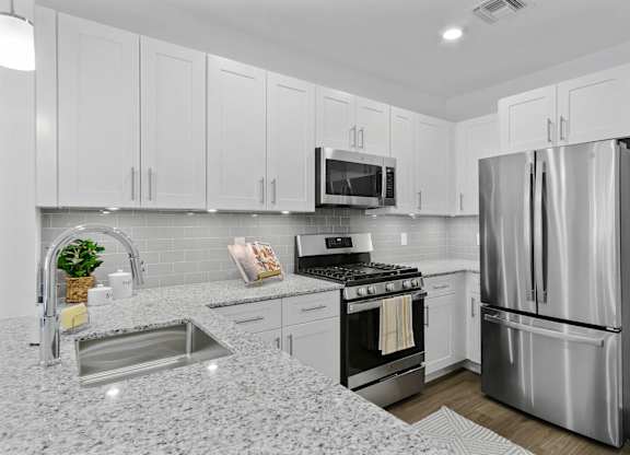 A modern kitchen with a stainless steel refrigerator and a granite countertop. at 10 N. Main Apartments, New Jersey