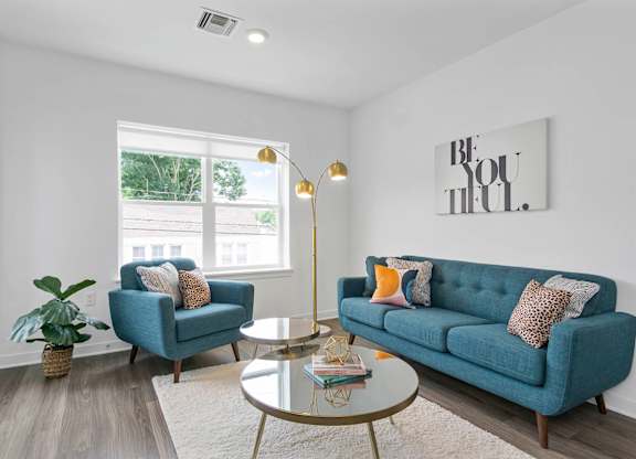 A living room with a blue couch and a coffee table at 10 N. Main Apartments, Wharton