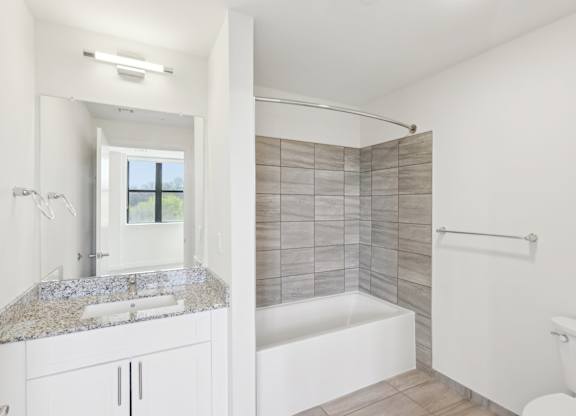 A white bathroom with a tub, sink, and toilet.