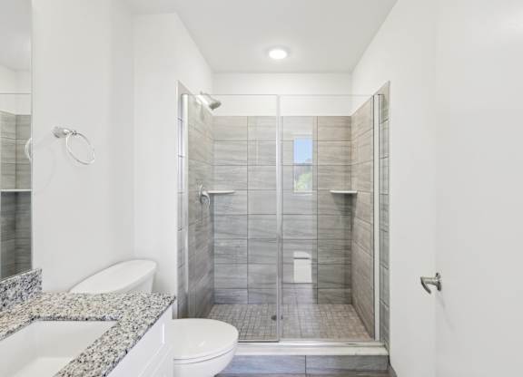 A white bathroom with a walk in shower and a toilet.