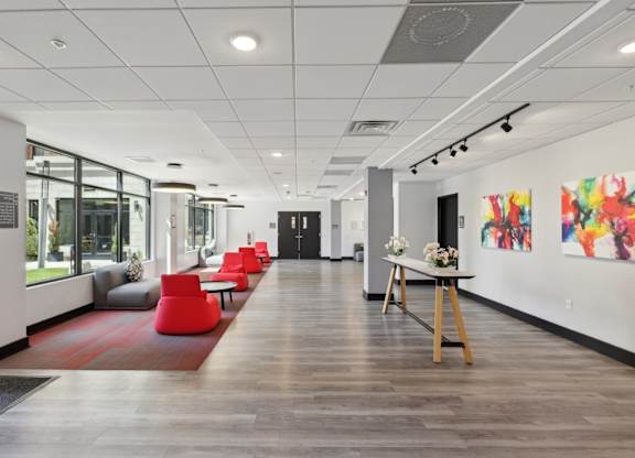 A long hallway with a red rug and chairs on the left side.