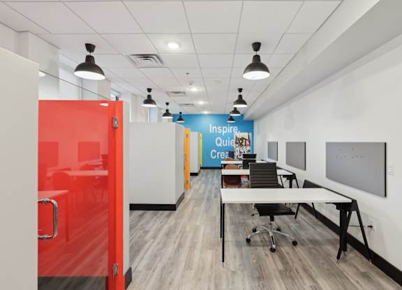 A room with a red door and a white wall with a blue banner that says Inspire Quietly Create.